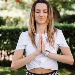 A serene moment of a woman practicing yoga with namaste pose outdoors, embracing mindfulness.