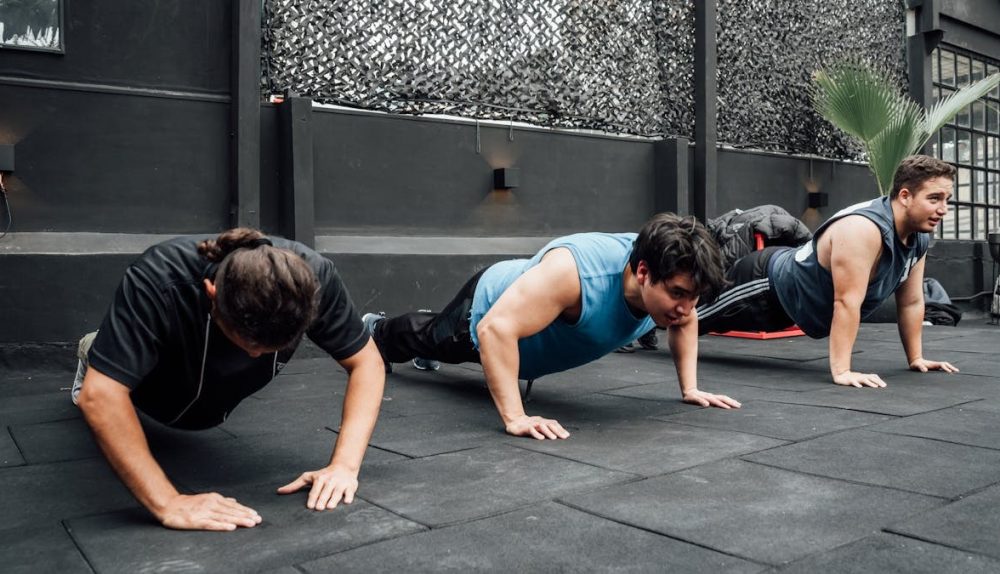 Men performing push-ups during a group workout session in Mexico City gym.